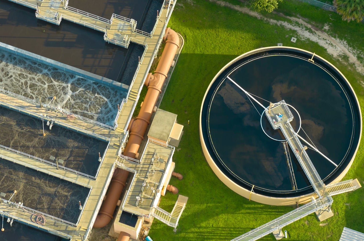 Water treatment plant with process tanks and pipework under a clear sky